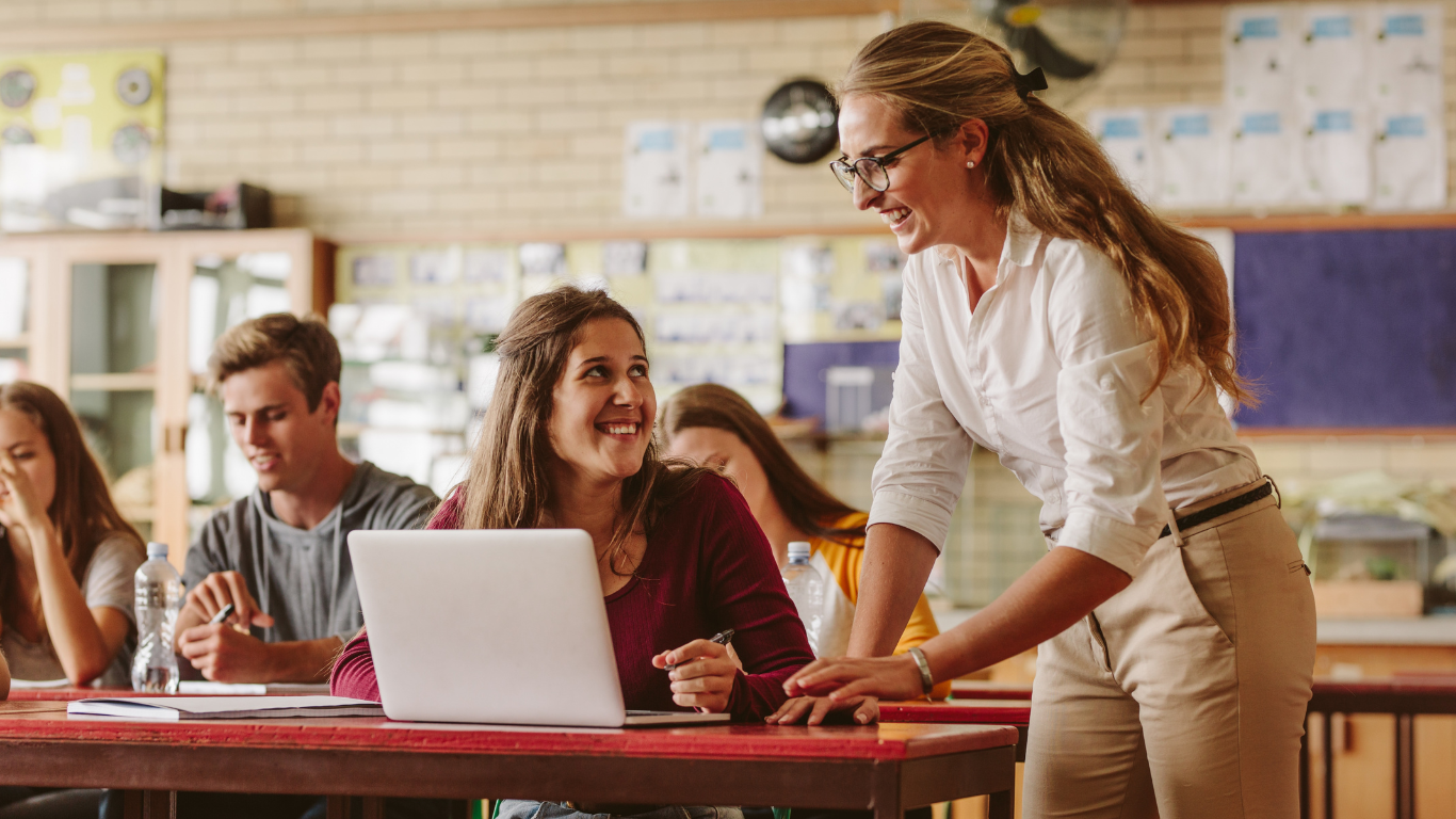 a teacher teaching students at a desk in a classroom