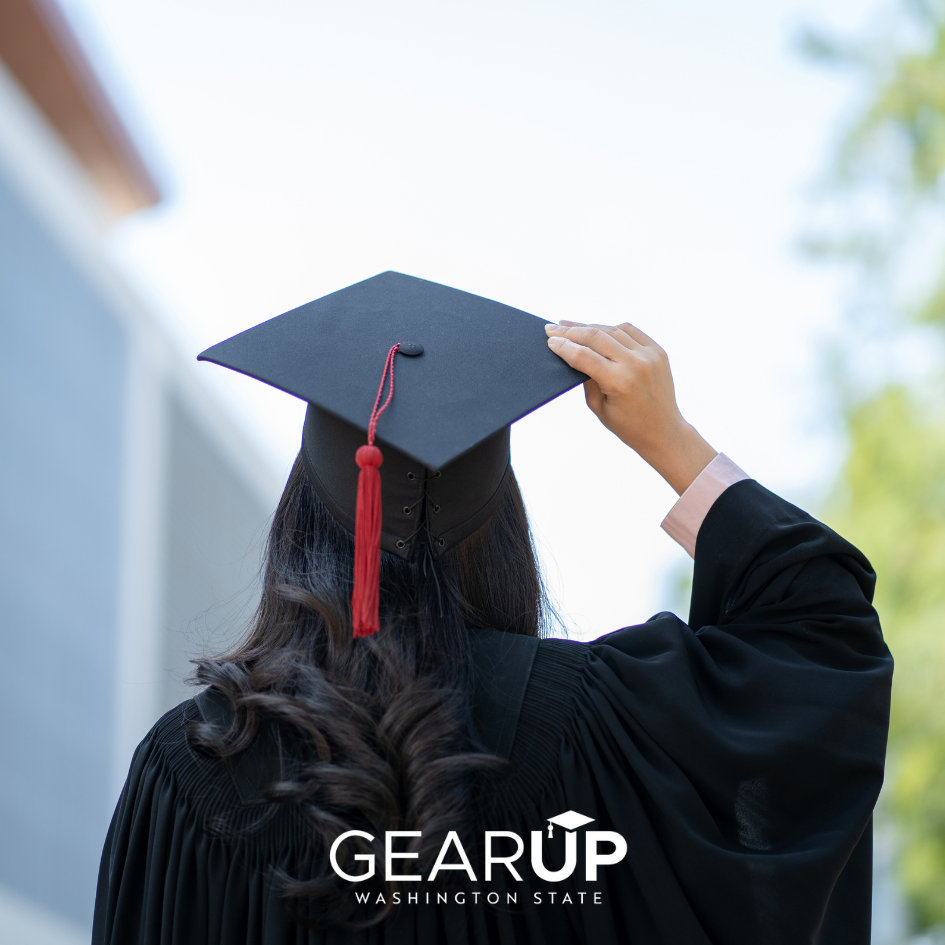 A person wearing a graduation cap and gown is standing in front of a building.